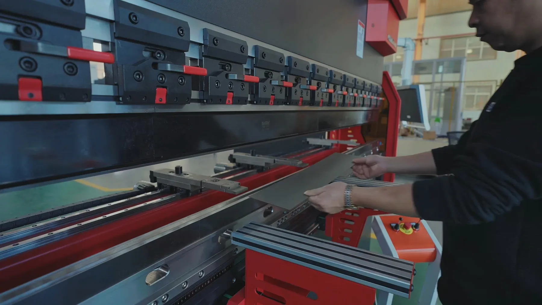 Worker positioning a sheet metal panel at a press brake machine in a fabrication workshop