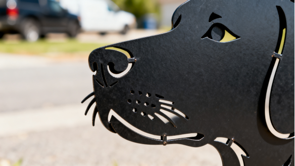 Powder-coated steel dog silhouette in a garden setting